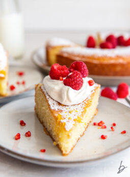 slice of french yogurt cake topped with whipped cream and raspberries.