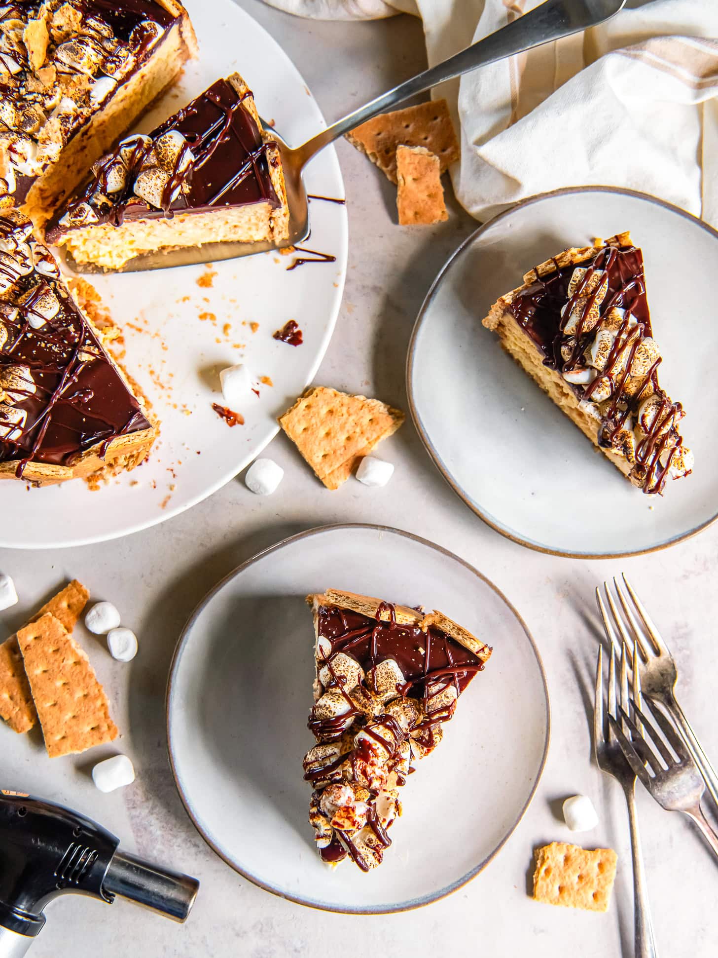 S'mores cheesecake sliced and served on white plates.