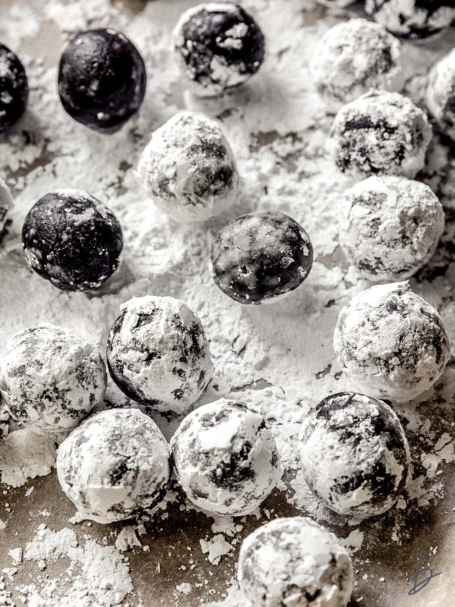 rum balls tossed in confectioners' sugar on a baking sheet.