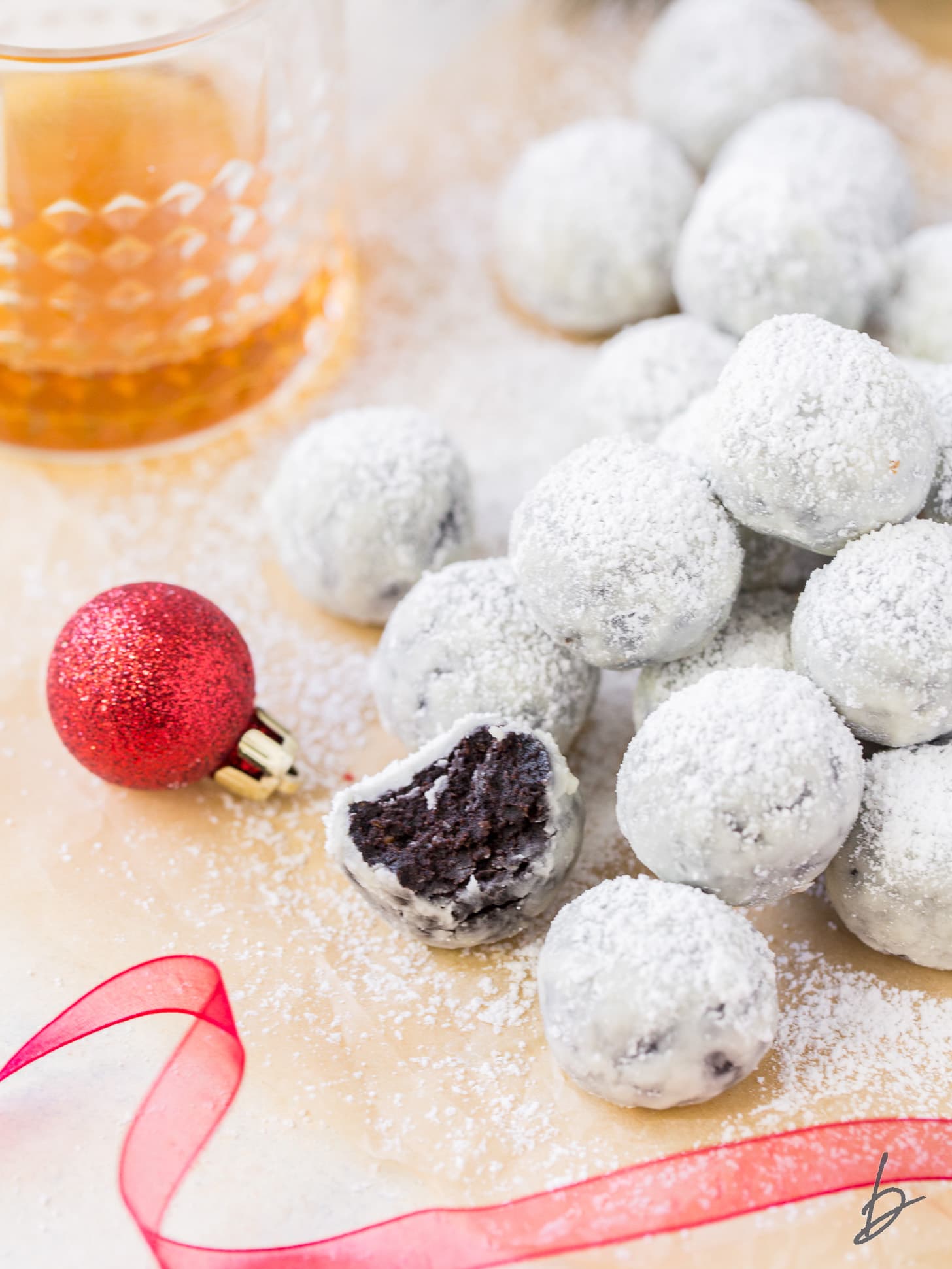 rum ball with a bite in front of pile of rum balls coated in confectioners' sugar.