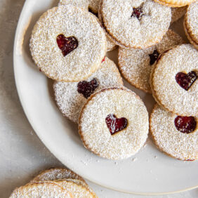 plate of raspberry jam sandwich cookies dusted with confectioners' sugar.