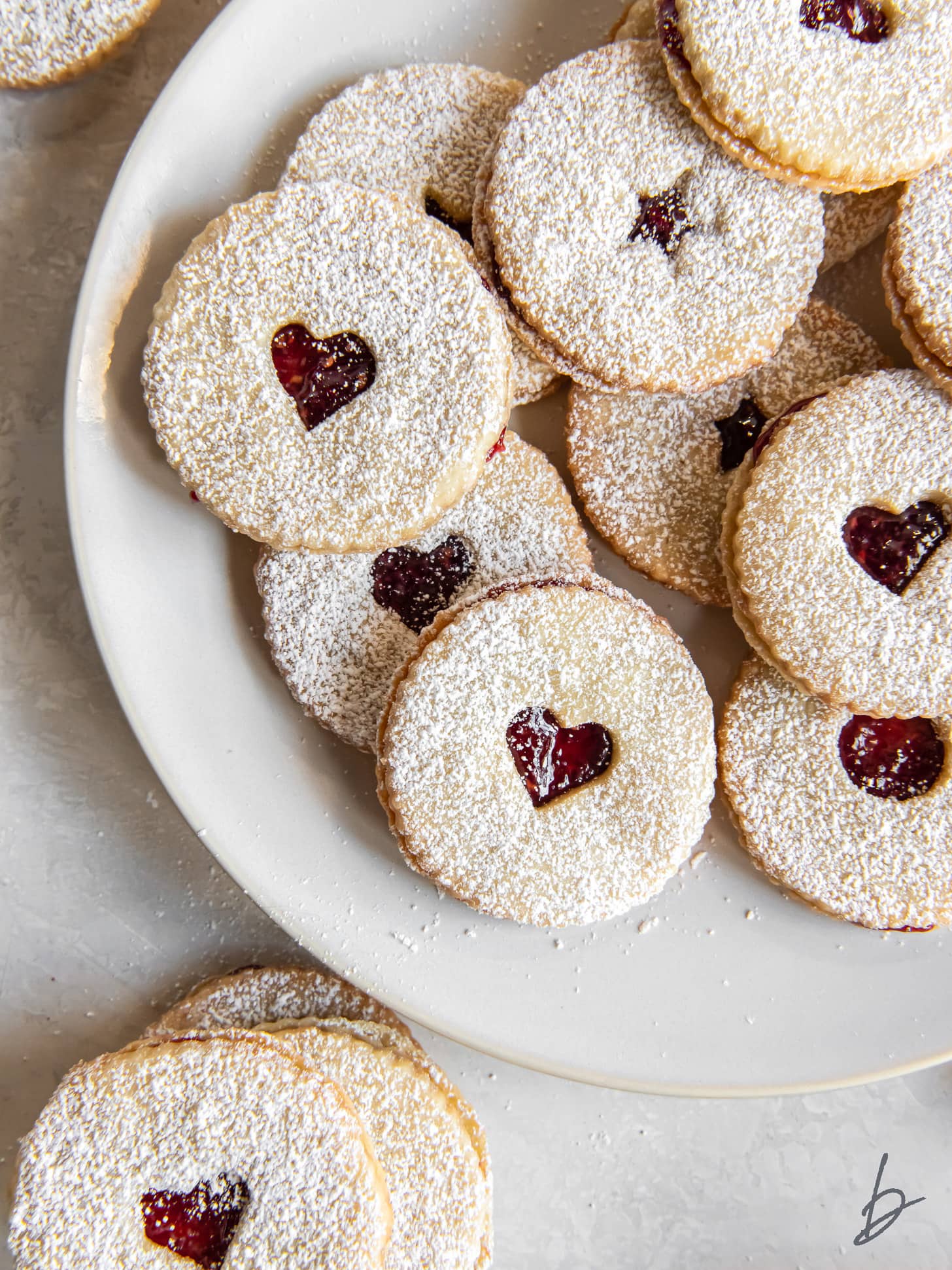 plate of raspberry jam sandwich cookies dusted with confectioners' sugar.