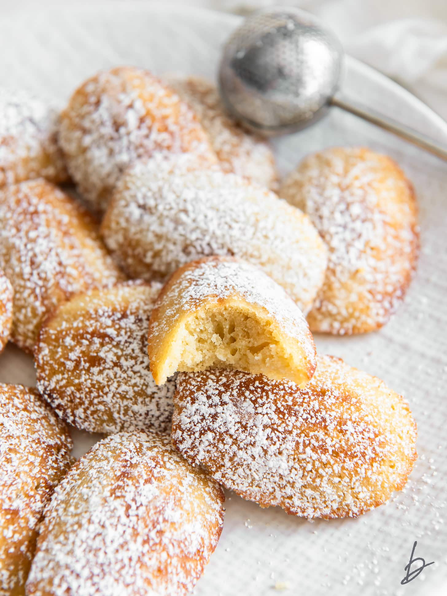 madeleine cookies on baking sheet with dusting of confectioners' sugar and lemon zest