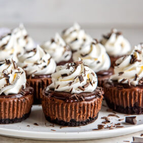 mini chocolate cheesecakes topped with whipped cream and chocolate shavings.