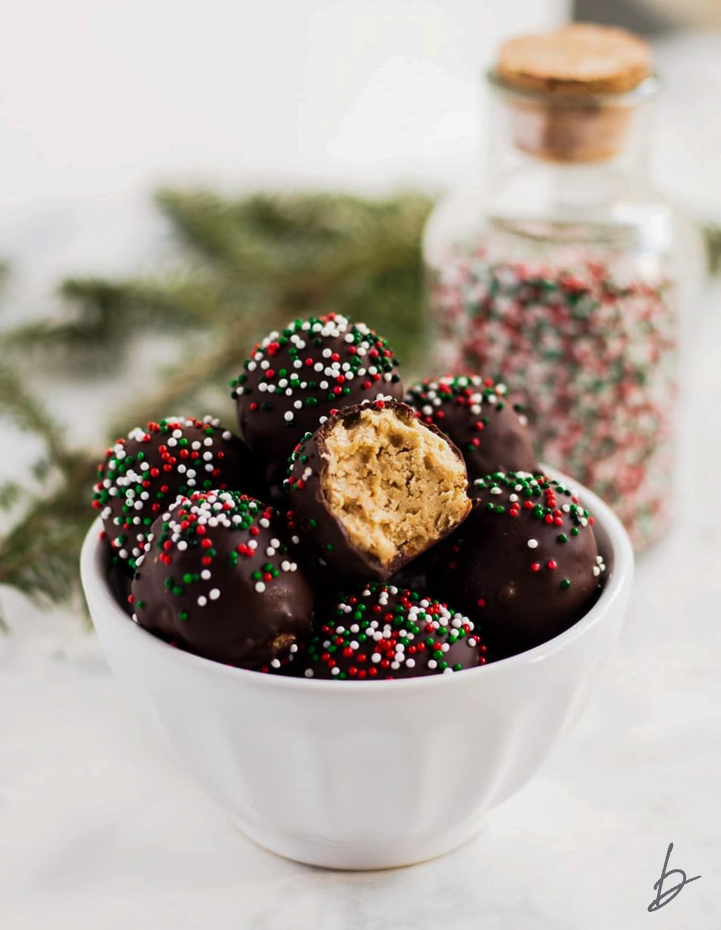 white bowl of peanut butter balls topped with Christmas sprinkles.