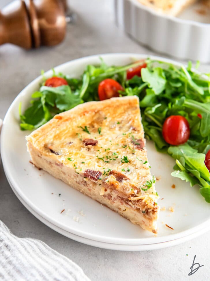 two slices of quiche on round plates with forks