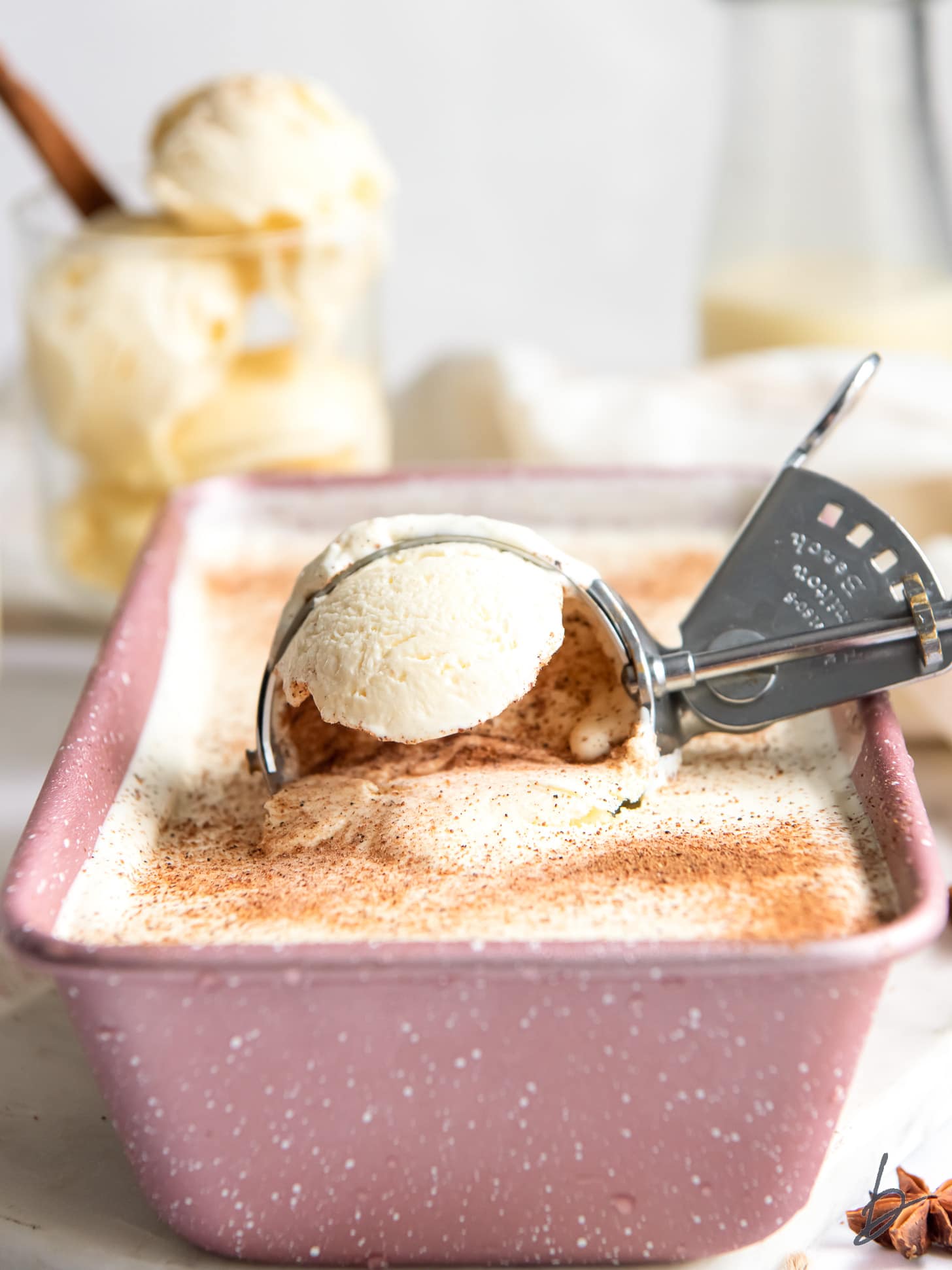 ice cream scoop scooping eggnog ice cream out of pink loaf pan.