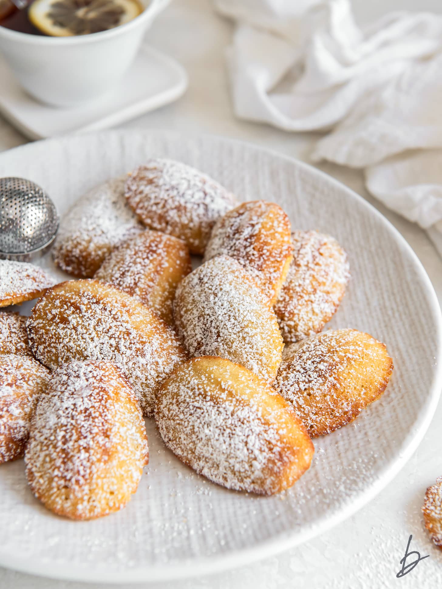 madeleines on a plate with a dusting of confectioners' sugar.