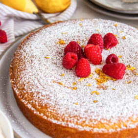 french yogurt cake garnished with dusting of confectioners' sugar and raspberries.