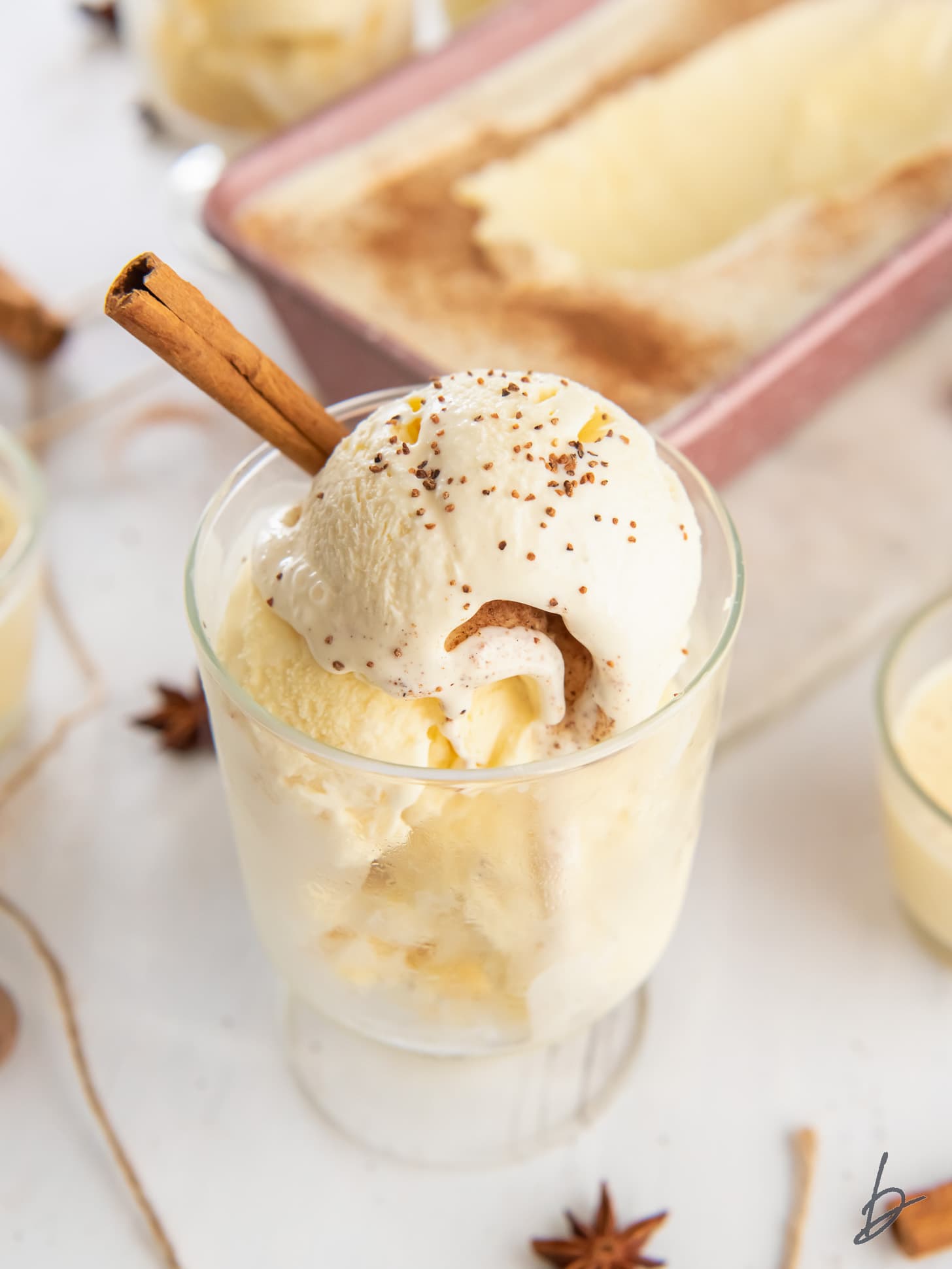 eggnog ice cream in glass sundae dish garnished with a cinnamon stick.