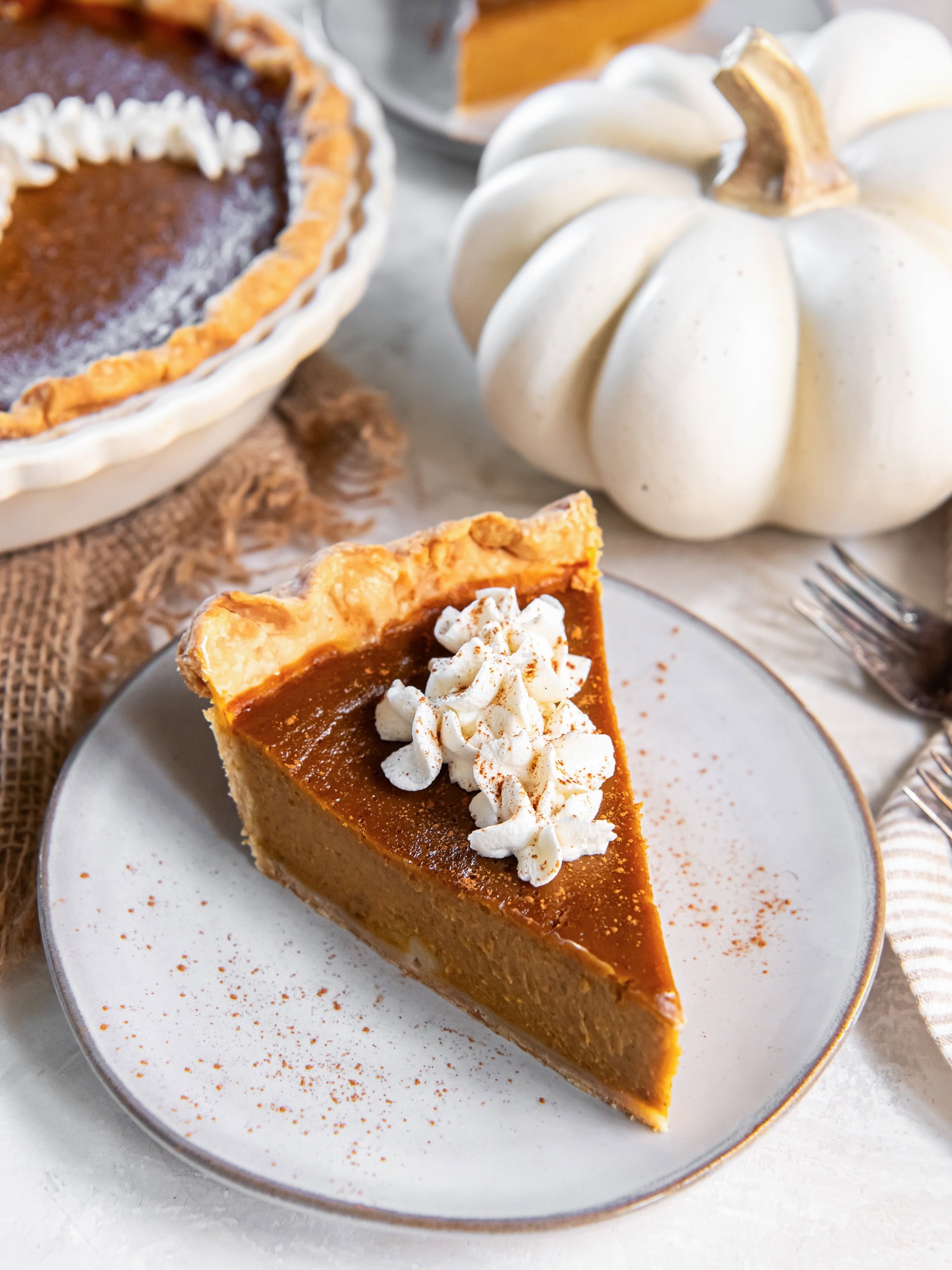 slice of pumpkin pie on plate with fork taking a bite.