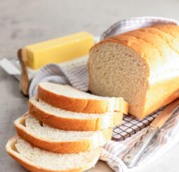 loaf of sandwich bread with four slices cut off one end and stick of butter next to bread.