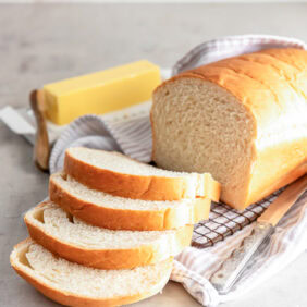 loaf of sandwich bread with four slices cut off one end and stick of butter next to bread.