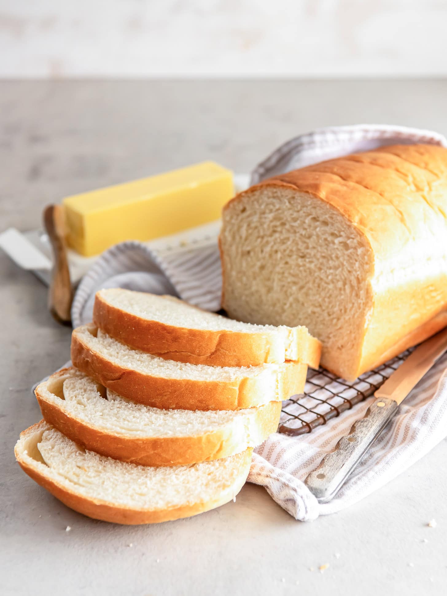 loaf of sandwich bread with four slices cut off one end and stick of butter next to bread.