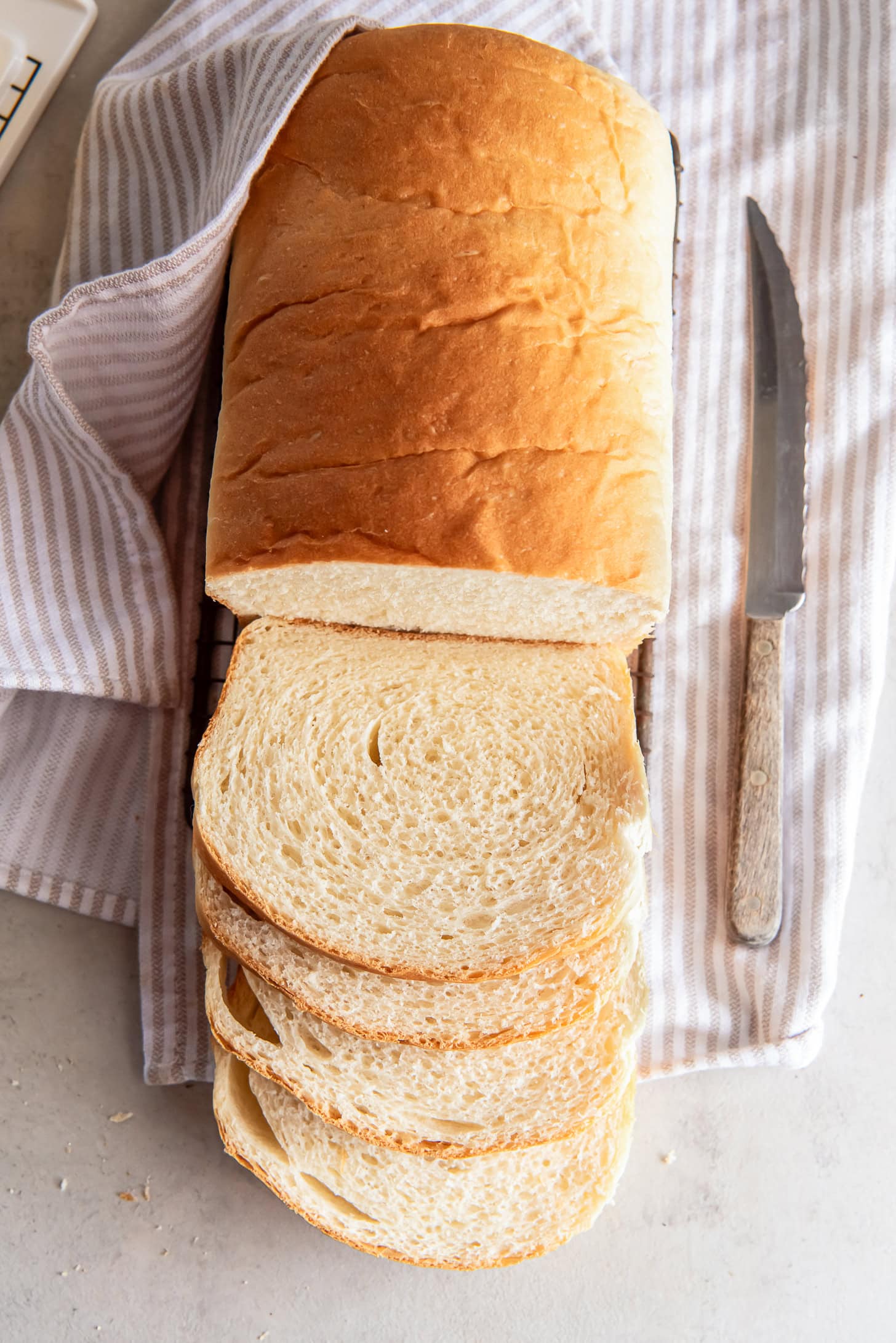 sandwich bread loaf sliced up on tabletop with striped kitchen cloth.