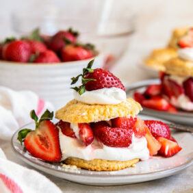 plate with strawberry shortcake showing layers of biscuit, whipped cream and berries.
