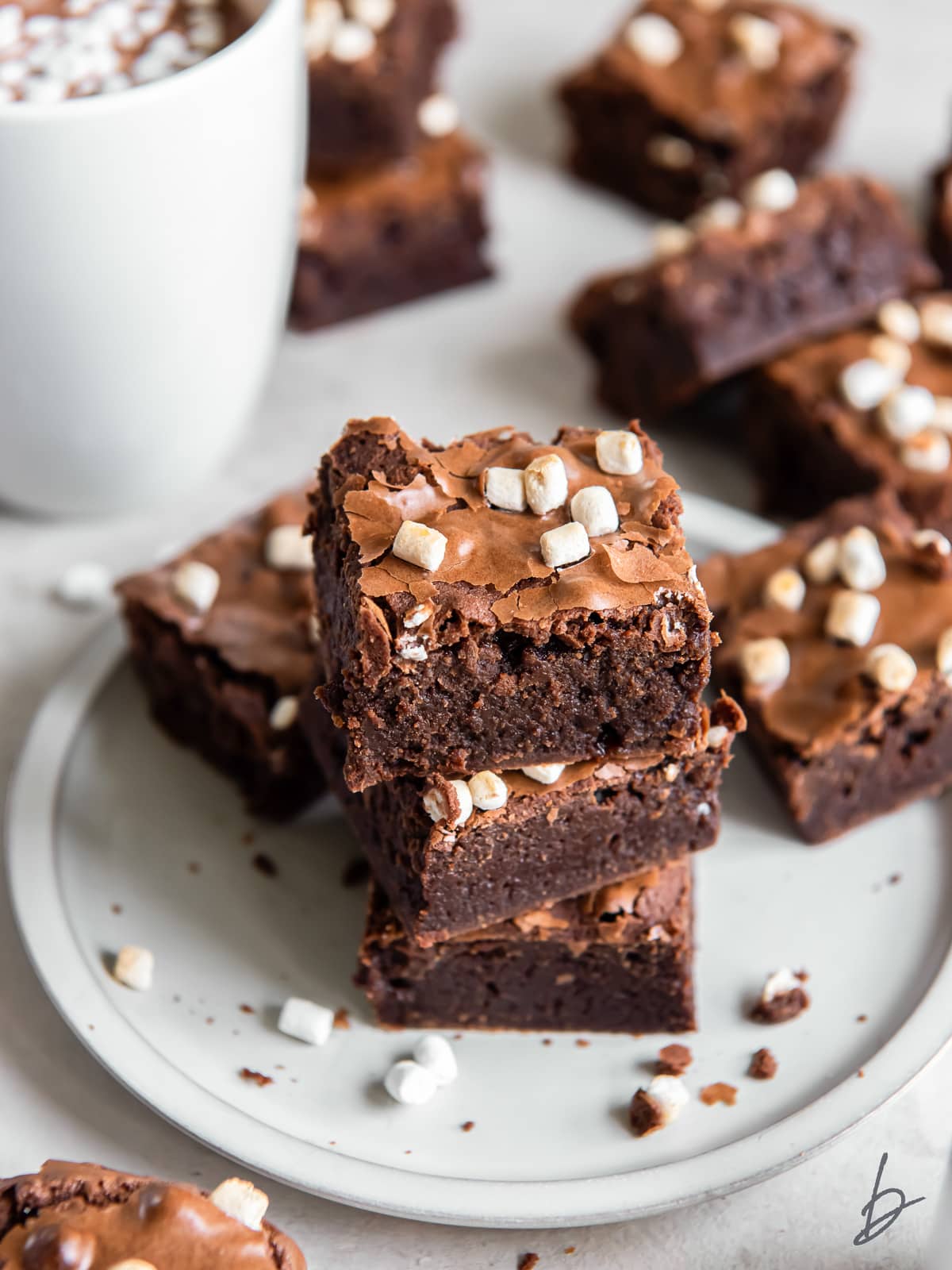 stack of hot cocoa brownies with mini marshmallows on a plate.