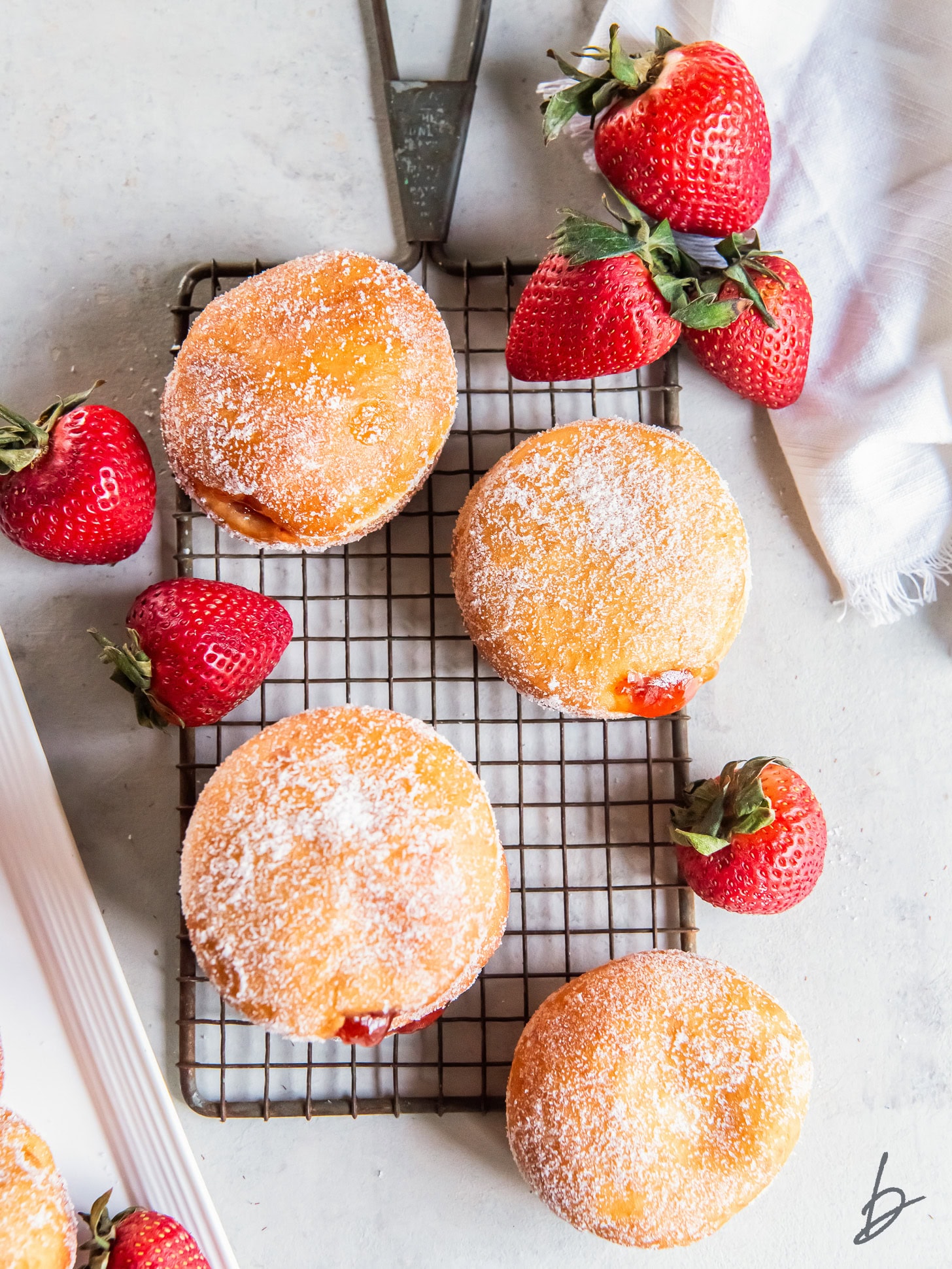 four jelly filled donuts on parchment paper in round pan with fresh strawberries