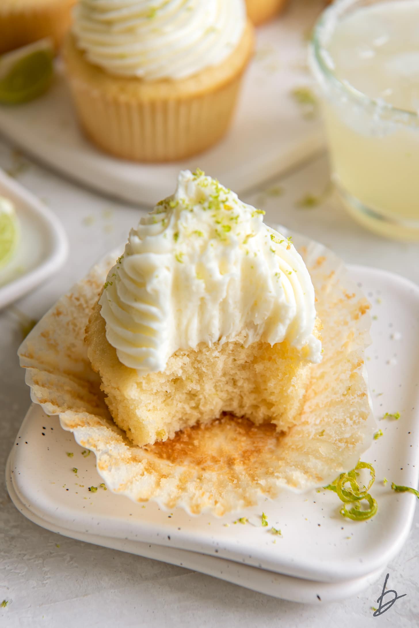 margarita cupcake with a bite sitting on unfolded paper liner.