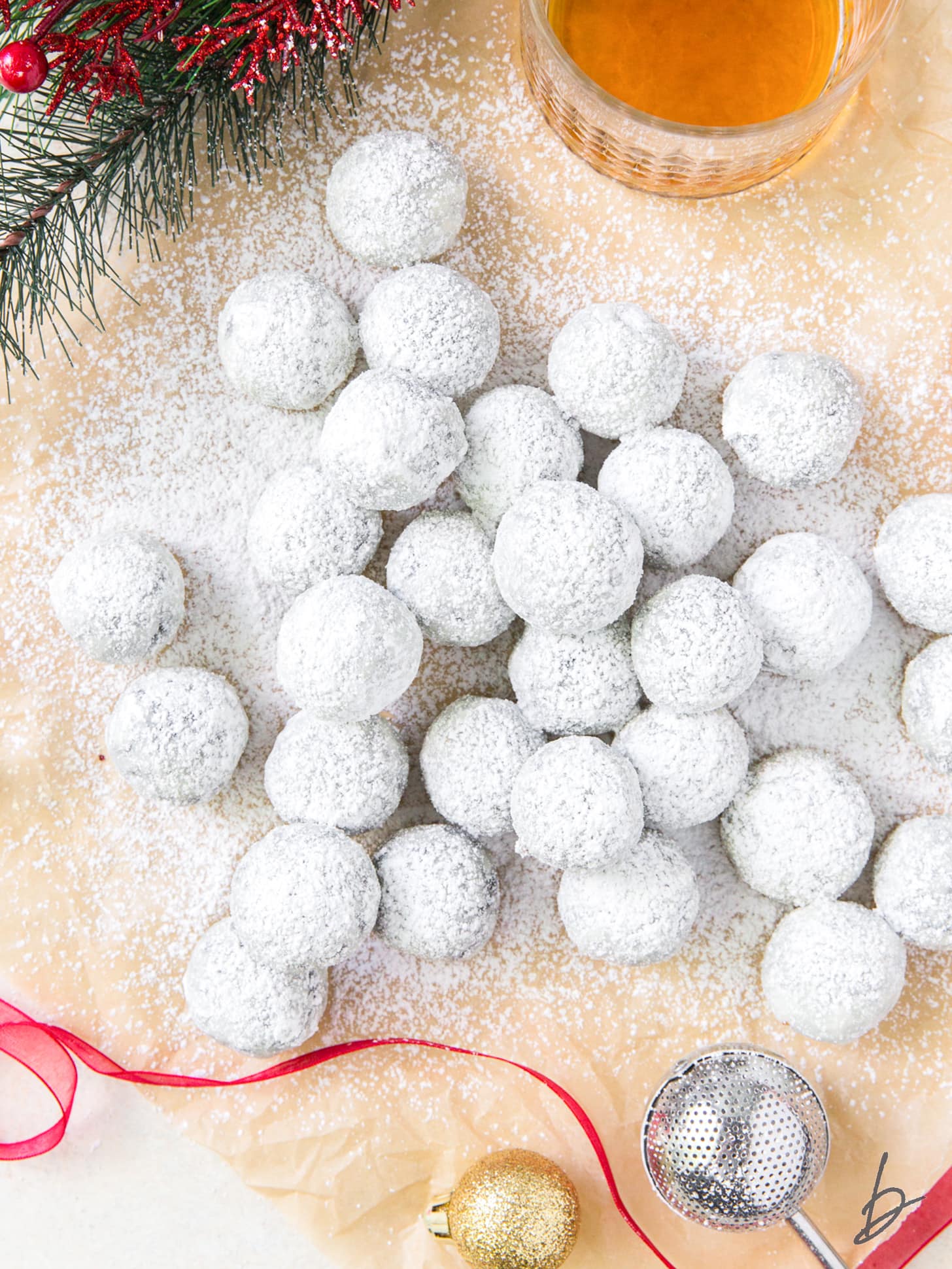 pile of rum balls coated in powdered sugar on a piece of parchment paper.