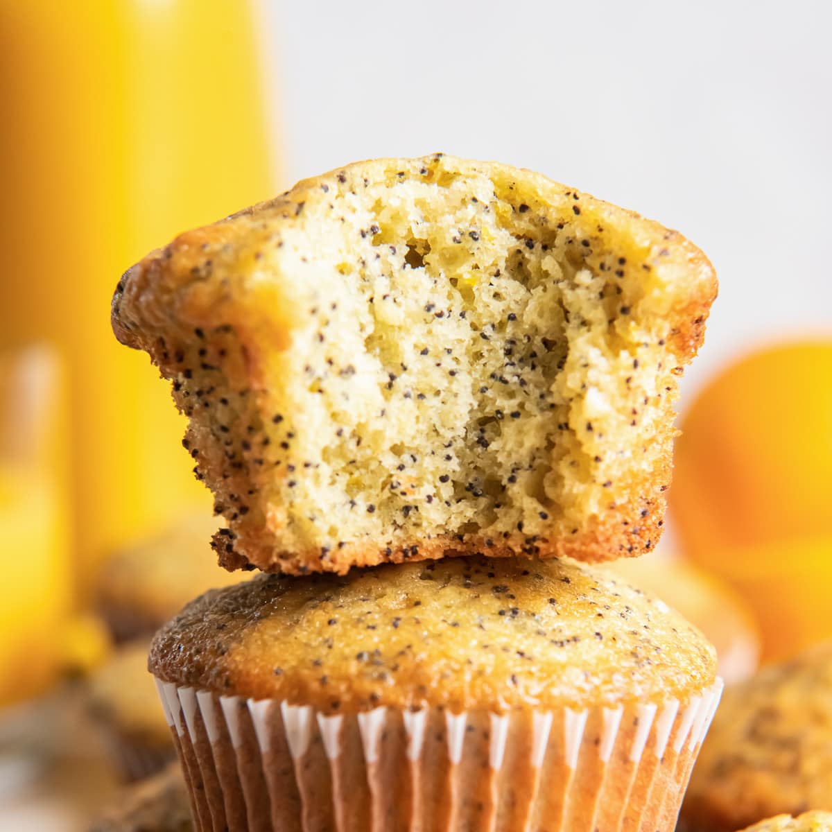 orange poppy seed muffin with a bite on top of another muffin.