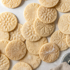 many shortbread stamped cookies dusted with sugar on a tabletop.