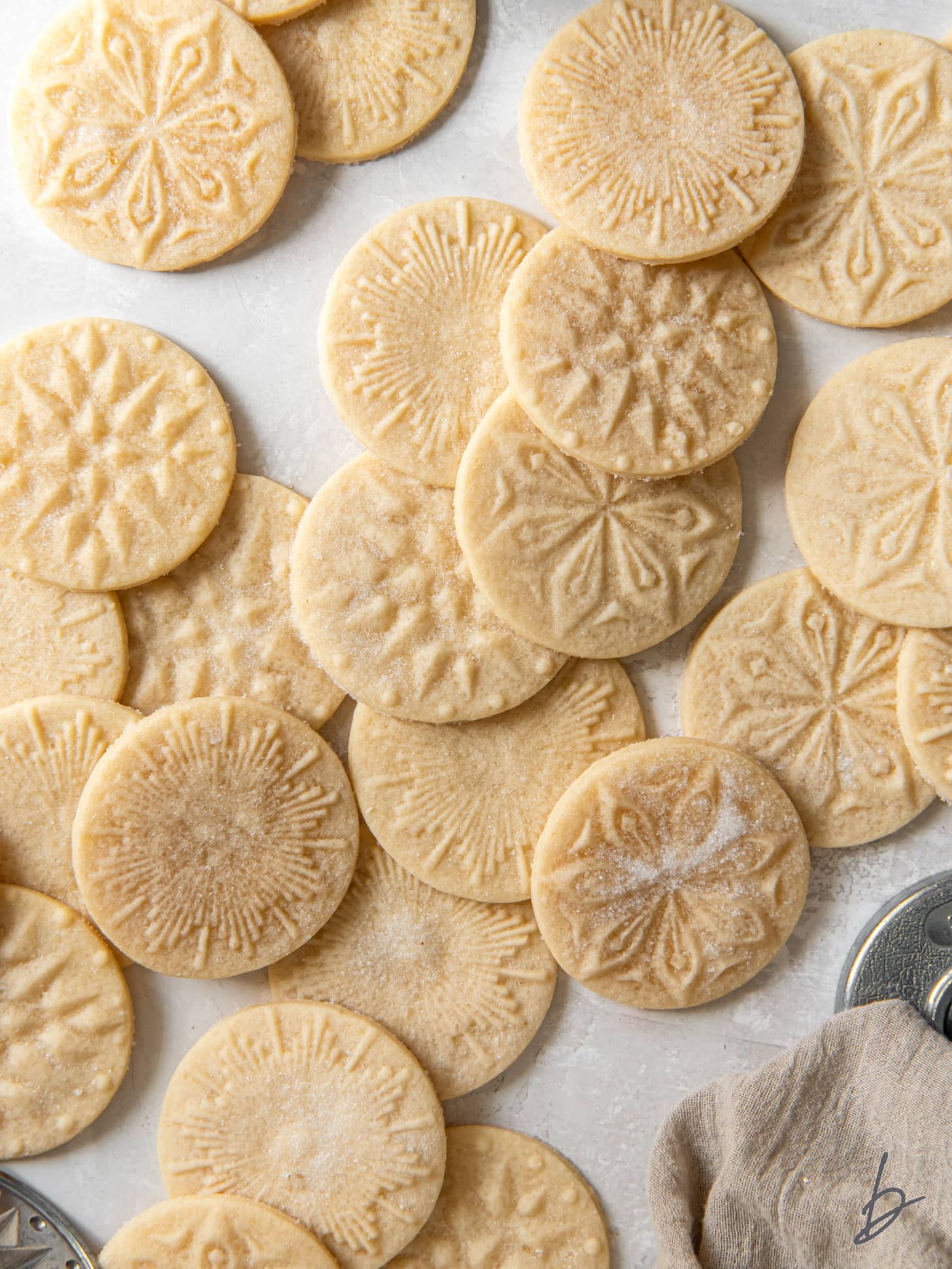 many shortbread stamped cookies dusted with sugar on a tabletop.