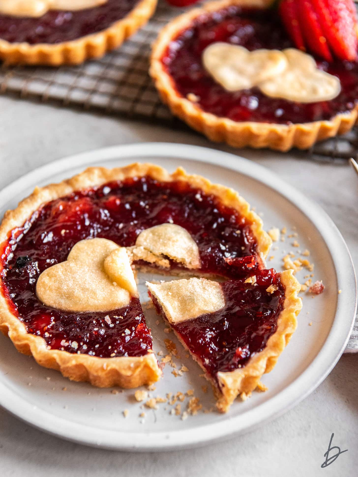 strawberry jam tart on a plate with a piece cut off.