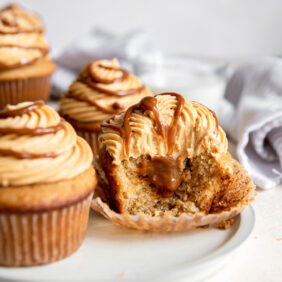 stuffed dulce de leche cupcake with a bite showing filling inside.