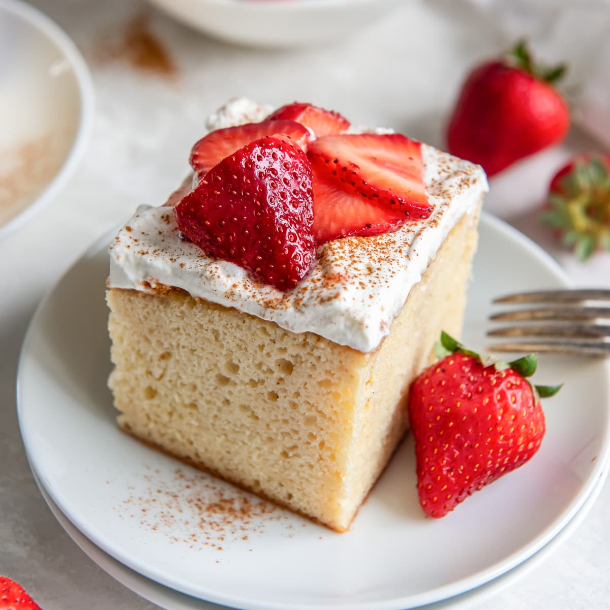 square piece of tres leches cake with strawberries on top.