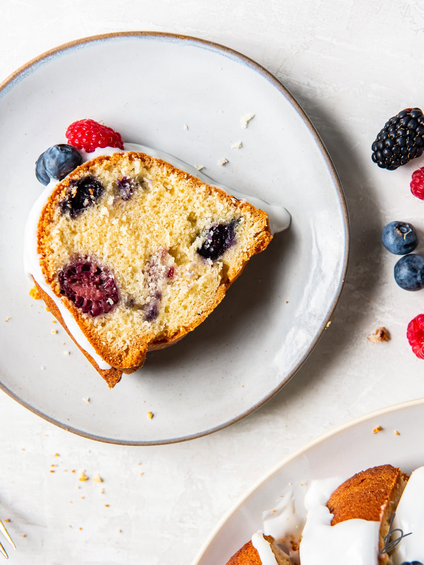 slice of triple berry pound cake on a plate on a tabletop.