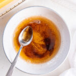 spoon in a bowl of brown butter next to butter dish.