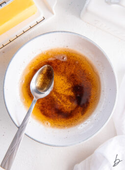 spoon in a bowl of brown butter next to butter dish.