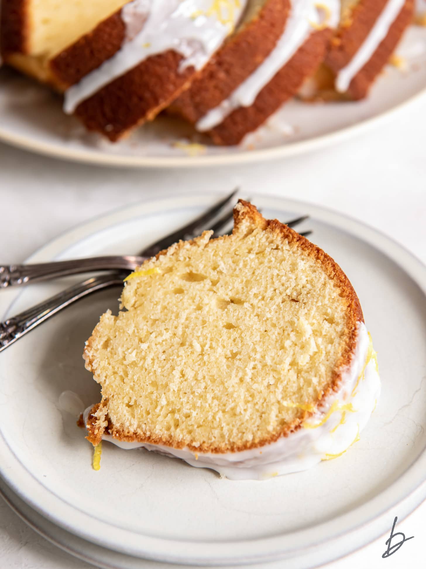 slice of lemon bundt cake on a round plate with a fork.