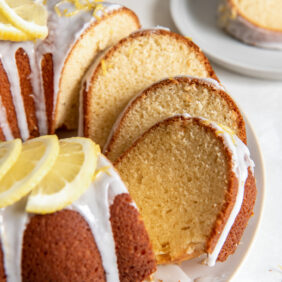 lemon bundt cake with slices leaning against each other on cake plate.