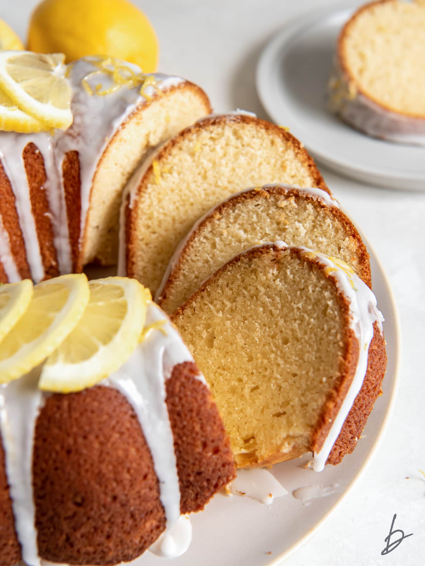 lemon bundt cake with slices leaning against each other on cake plate.