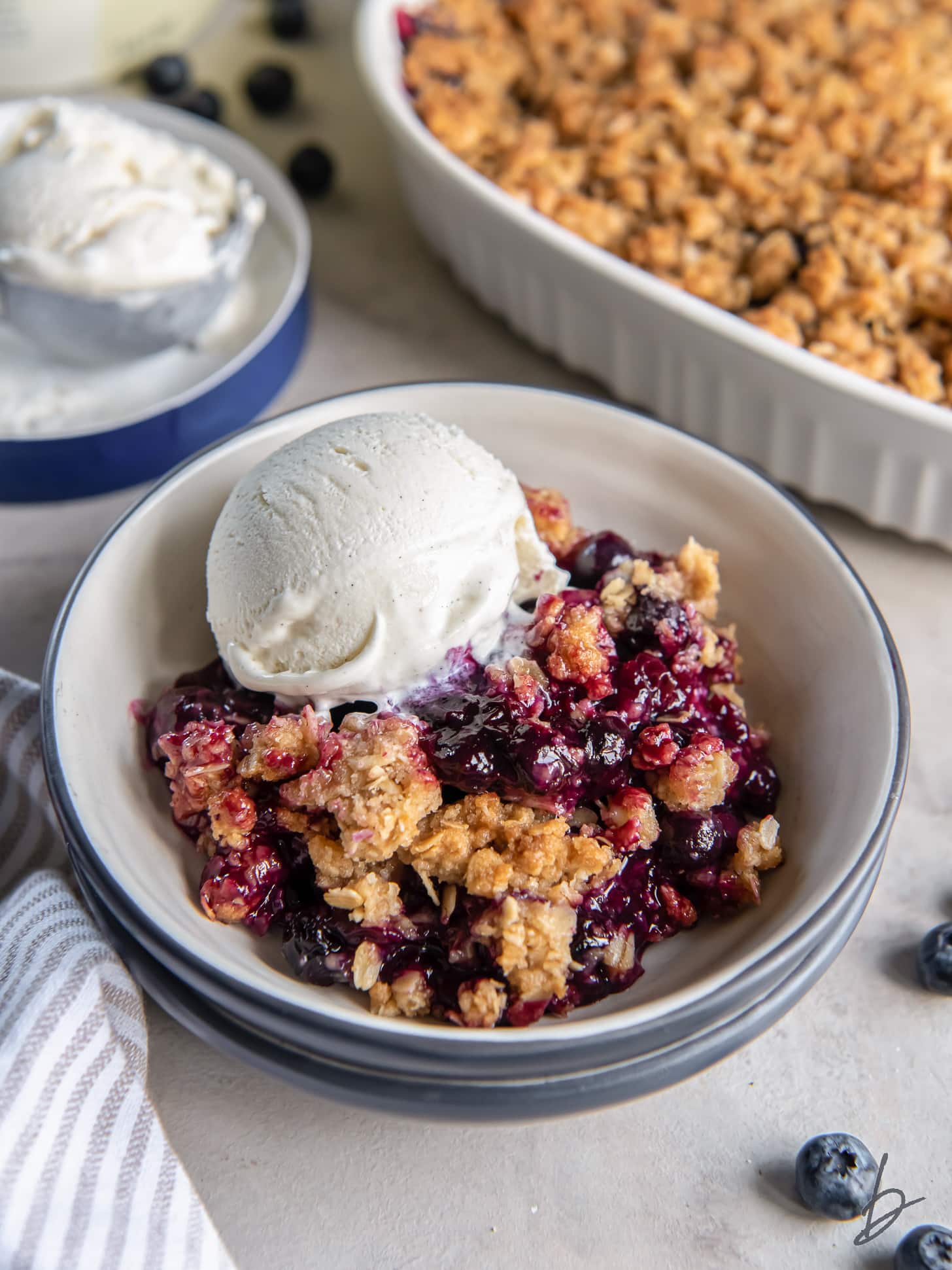bowl of blueberry crisp with oats and vanilla ice cream.