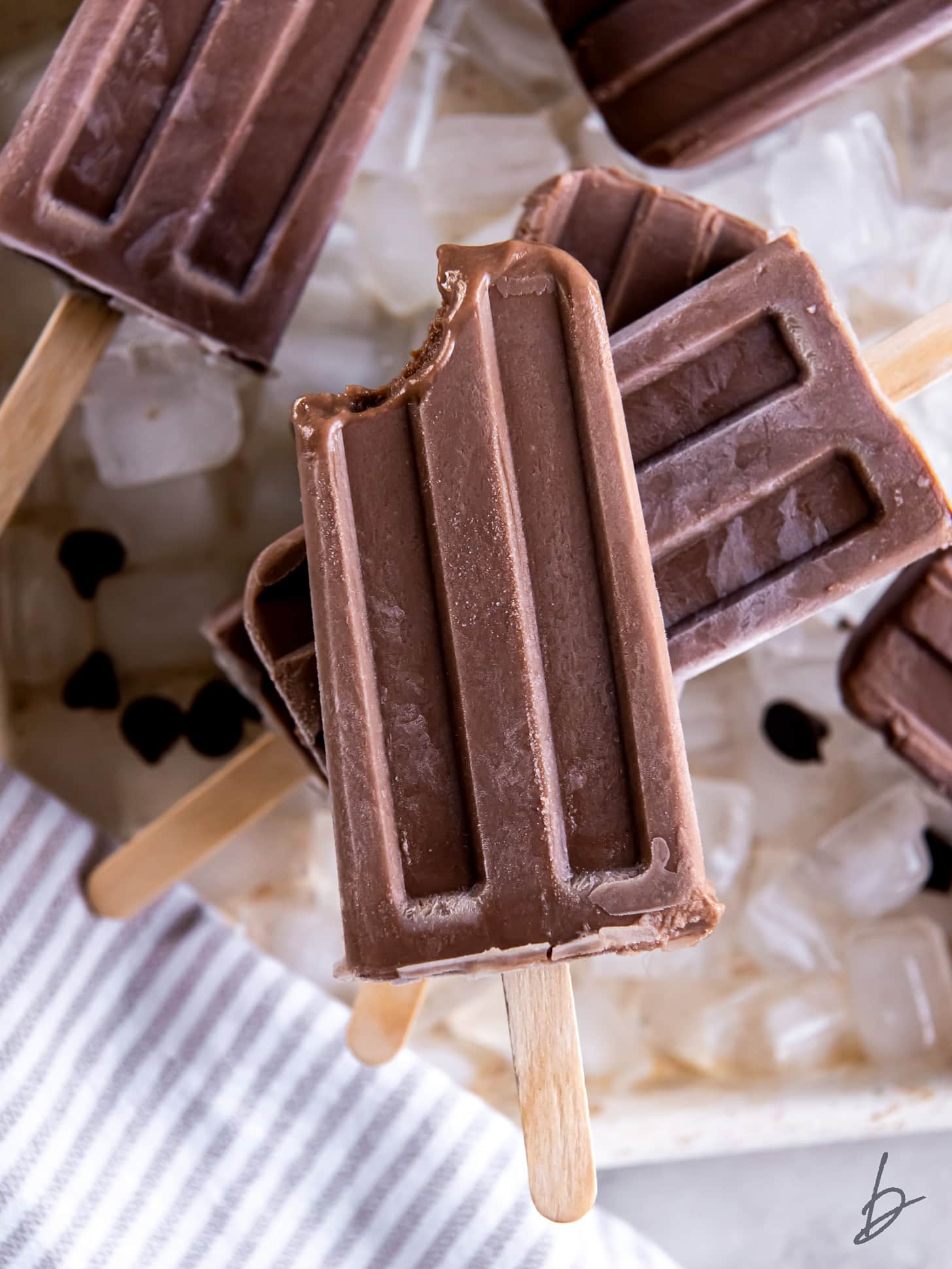 fudgesicle with a bite taken sitting on top of more popsicles.