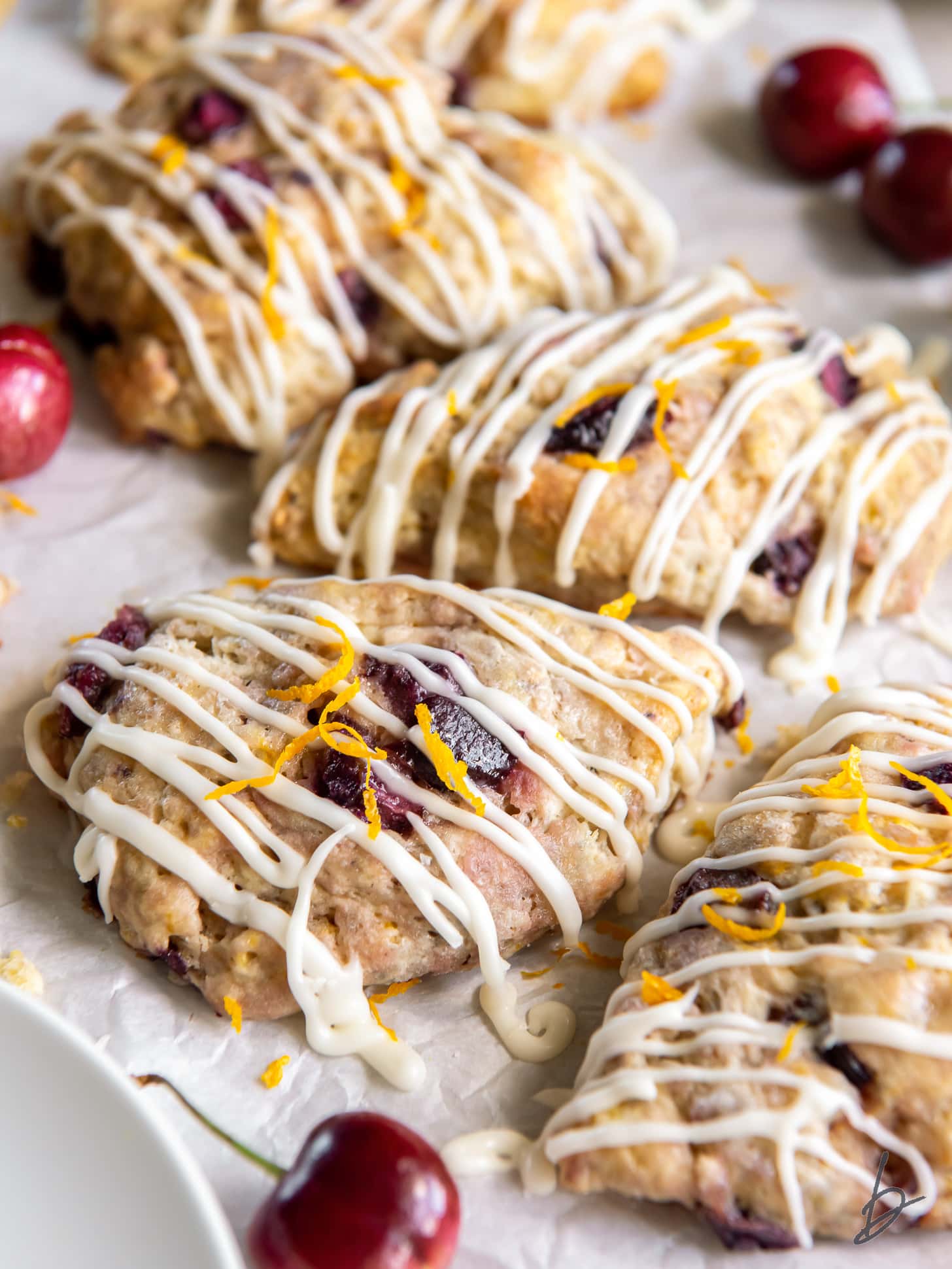 cherry scones with orange glaze on parchment paper.