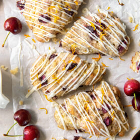 cherry scones with orange glaze on parchment paper.