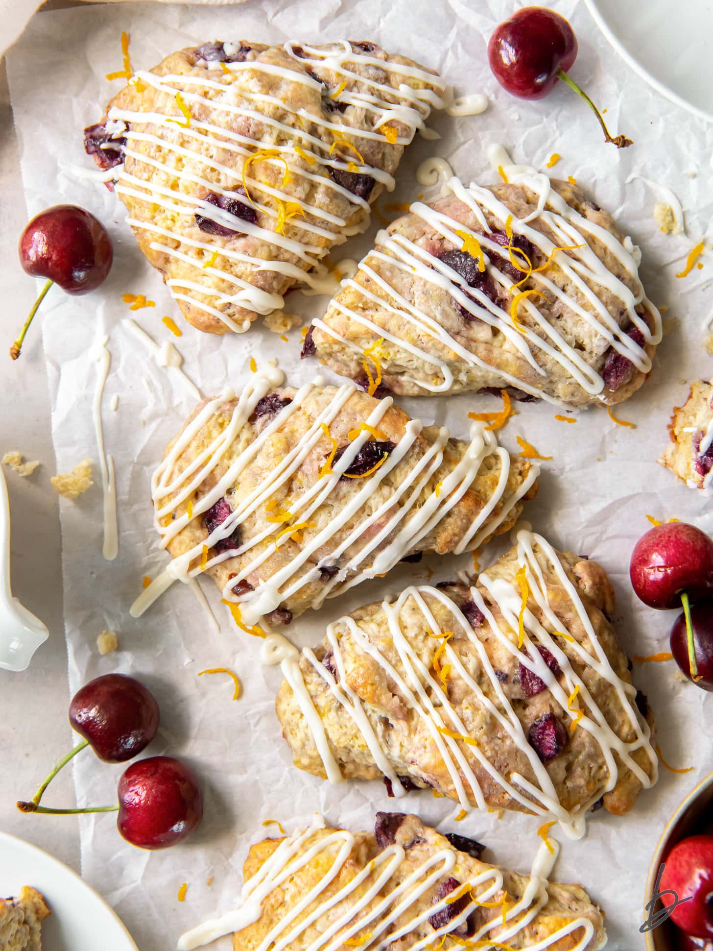 cherry scones with orange glaze on parchment paper.