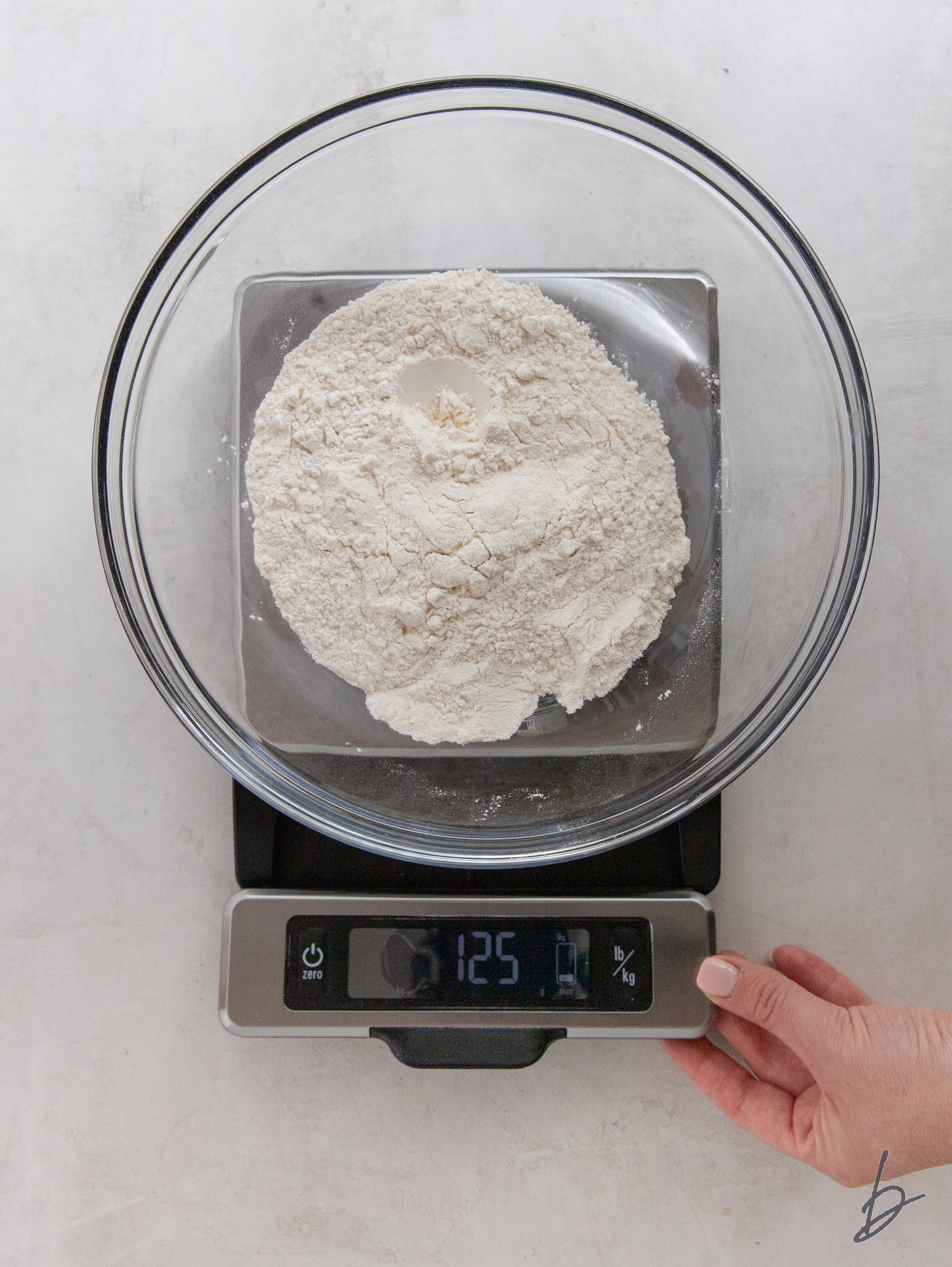 flour in a glass bowl on a kitchen scale reading 125 g.