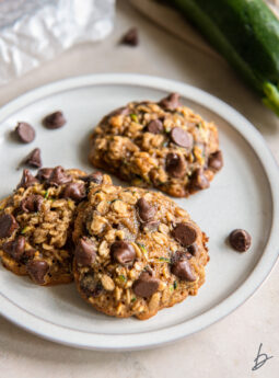 three zucchini chocolate chip cookies on a plate.