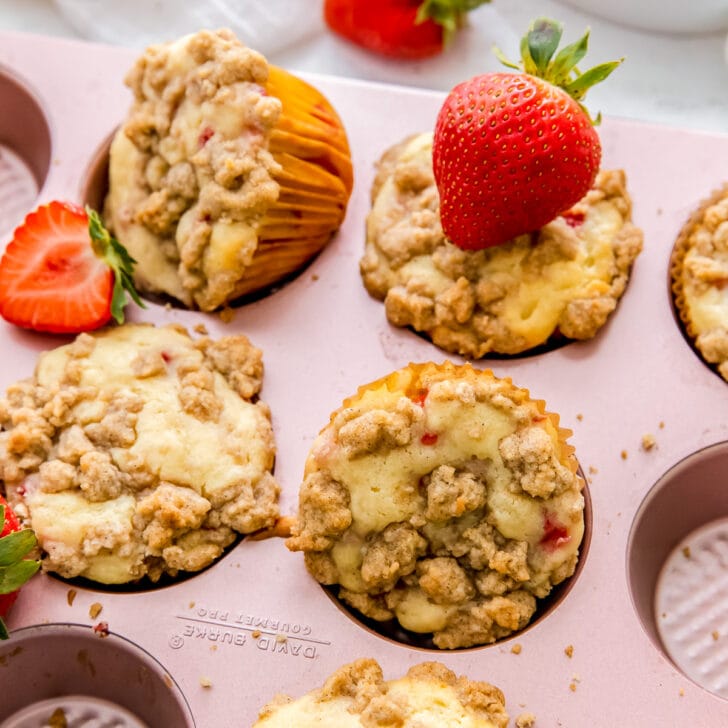 strawberry muffins with crumble in a pink muffin tin.