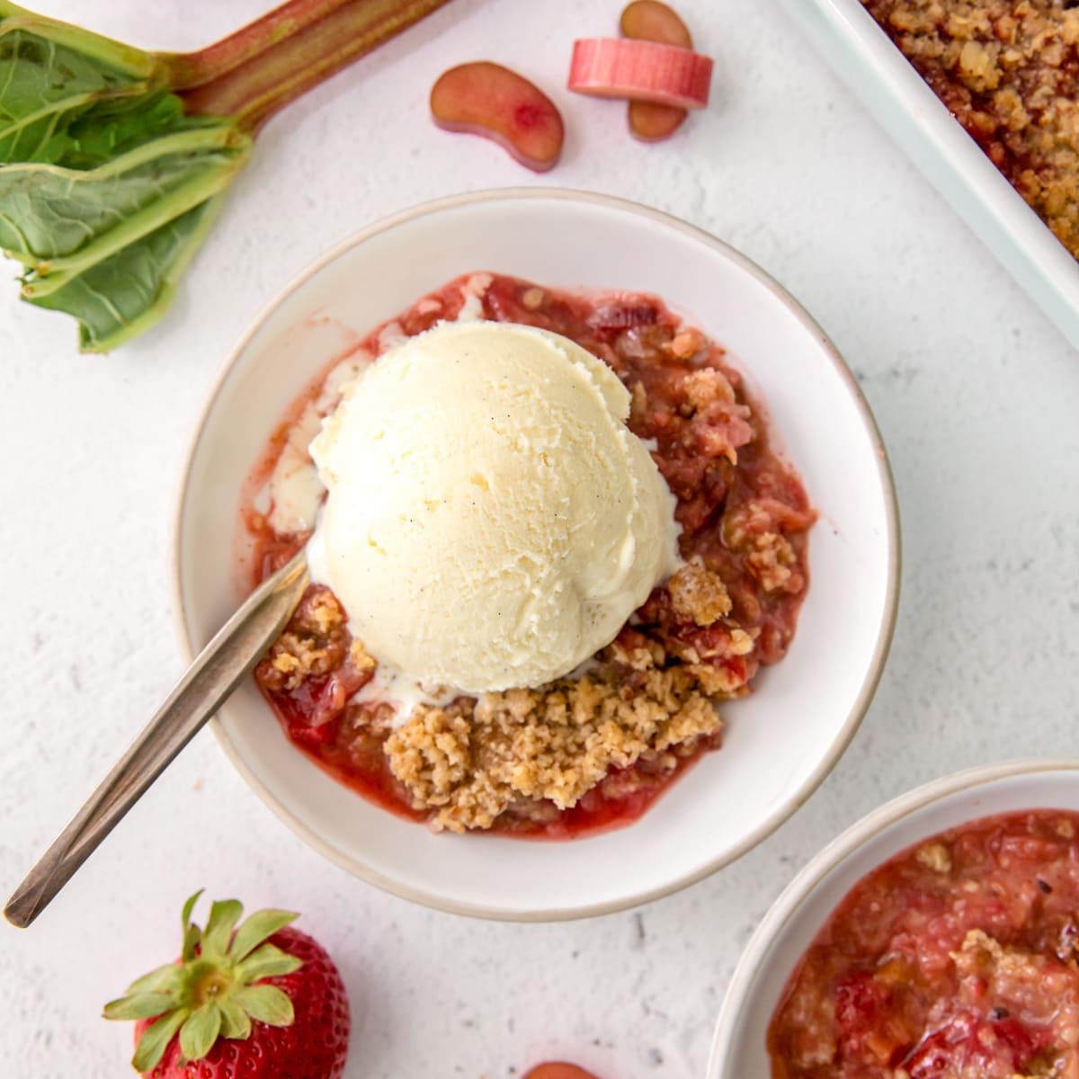 bowl of strawberry rhubarb crisp with a scoop of vanilla ice cream.