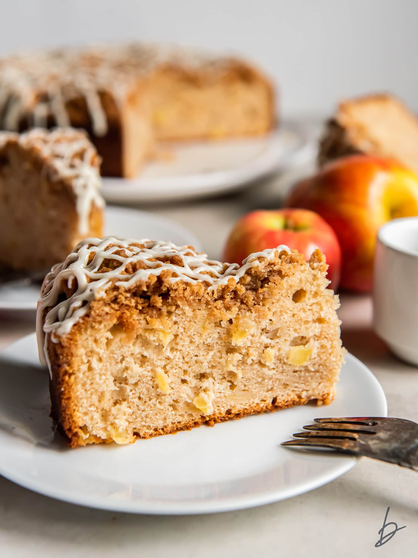 slice of apple coffee cake on a plate with bits of apples inside.