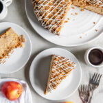 tabletop with apple coffee cake with streusel topping and a piece put on a plate.