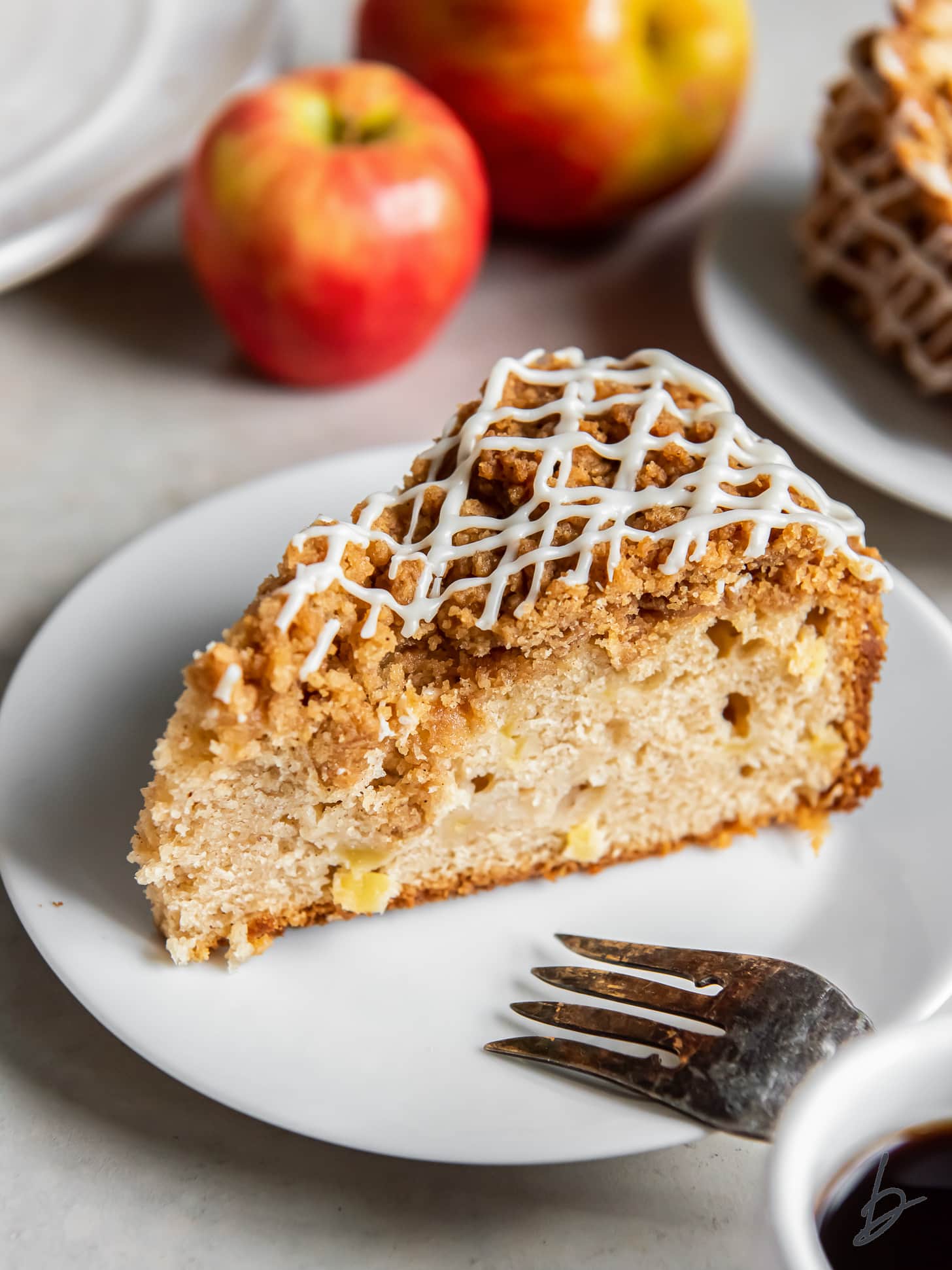 slice of apple coffee cake with maple icing on a plate with a fork.