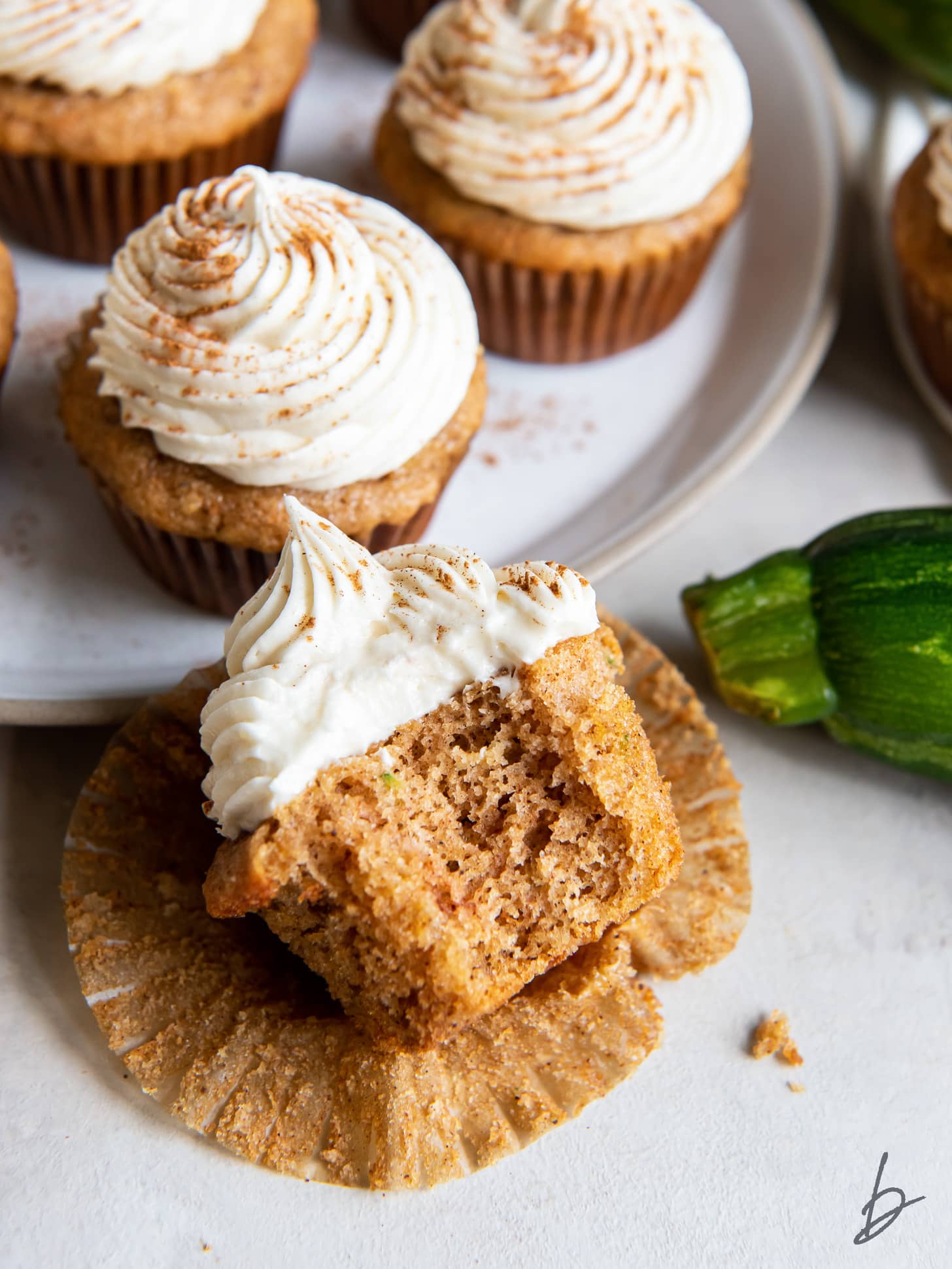 zucchini cupcake with a bite leaning on open paper liner.