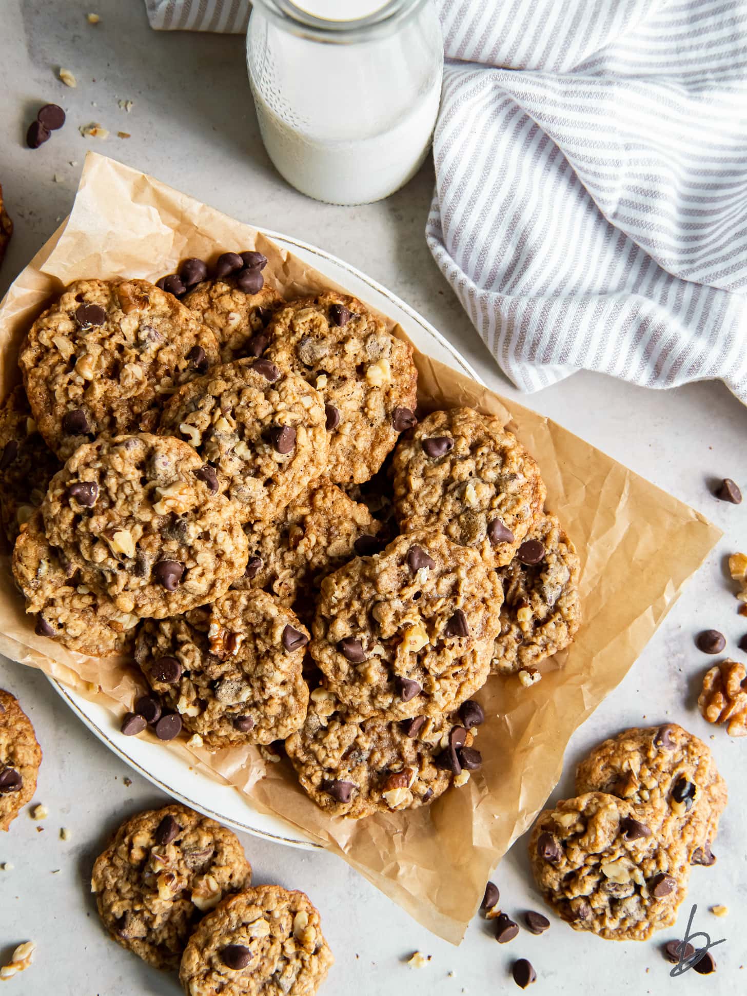 pile of walnut oatmeal cookies on parchment paper on a plate.